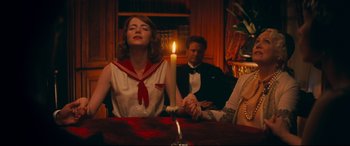Movie still from “Magic in the Moonlight” (2014), directed by Woody Allen – A woman sitting at a table with a candle in front of a man and woman; Medium shot, High angle