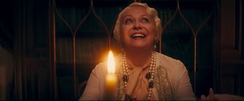 Movie still from “Magic in the Moonlight” (2014), directed by Woody Allen – An older woman is smiling while holding a lit candle; Close Up shot, Low angle