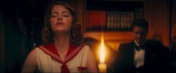 Movie still from “Magic in the Moonlight” (2014), directed by Woody Allen – A woman in a sailor's uniform meditates in front of a candle; Close Up shot, High angle