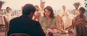 Movie still from “Magic in the Moonlight” (2014), directed by Woody Allen – A woman sitting at a table with a cake; Medium shot, Over the shoulder angle