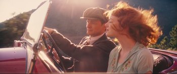 Movie still from “Magic in the Moonlight” (2014), directed by Woody Allen – A man and a woman driving a car in the sunlight; Medium shot, Low angle