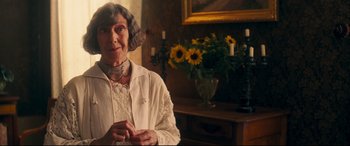 Movie still from “Magic in the Moonlight” (2014), directed by Woody Allen – An older woman in a white shirt and a necklace; Medium shot, Over the shoulder angle
