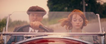 Movie still from “Magic in the Moonlight” (2014), directed by Woody Allen – A man and a woman driving a car in the road; Medium shot, Over the shoulder angle