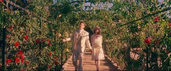 Movie still from “Magic in the Moonlight” (2014), directed by Woody Allen – A man and a woman holding hands while walking across a bridge; Wide shot, High angle