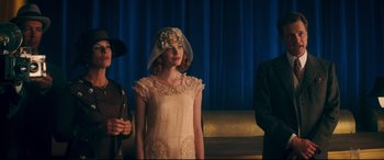Movie still from “Magic in the Moonlight” (2014), directed by Woody Allen – A woman in a white dress standing next to a man in a black suit; Medium shot, Over the shoulder angle
