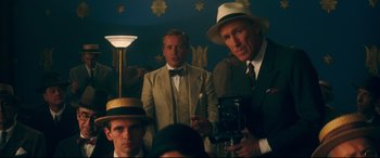 Movie still from “Magic in the Moonlight” (2014), directed by Woody Allen – A group of men standing next to each other in a room; Medium shot, Low angle