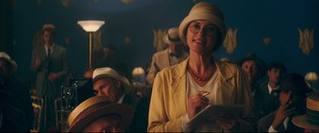 Movie still from “Magic in the Moonlight” (2014), directed by Woody Allen – A woman wearing a hat and a yellow jacket; Medium shot, Over the shoulder angle