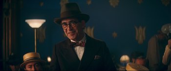 Movie still from “Magic in the Moonlight” (2014), directed by Woody Allen – An older man wearing a suit and bow tie; Medium shot, Over the shoulder angle