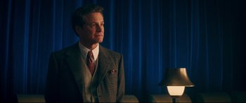 Movie still from “Magic in the Moonlight” (2014), directed by Woody Allen – A man in a suit and tie standing in front of a lamp; Medium shot, Low angle