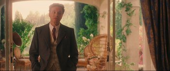 Movie still from “Magic in the Moonlight” (2014), directed by Woody Allen – A man in a suit standing in front of an open door; Medium shot, Over the shoulder angle