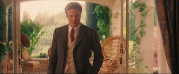 Movie still from “Magic in the Moonlight” (2014), directed by Woody Allen – A man in a suit and tie standing in front of a chair; Medium shot, Over the shoulder angle