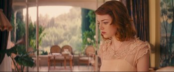 Movie still from “Magic in the Moonlight” (2014), directed by Woody Allen – A young woman in a beige dress is standing in front of chairs; Medium shot, Over the shoulder angle