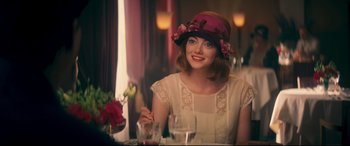Movie still from “Magic in the Moonlight” (2014), directed by Woody Allen – A woman sitting at a table with a glass of wine; Medium shot, Over the shoulder angle