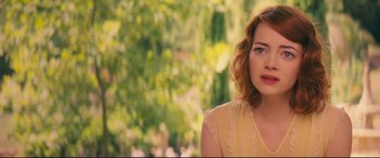 Movie still from “Magic in the Moonlight” (2014), directed by Woody Allen – A woman in a yellow dress is standing in front of trees; Close Up shot, Over the shoulder angle