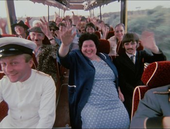 Movie still from “Magical Mystery Tour” (1967), directed by Ringo Starr – A group of people riding on a bus waving at the camera; Wide shot, High angle
