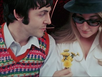 Movie still from “Magical Mystery Tour” (1967), directed by Ringo Starr – A man and a woman holding a yellow flower; Close Up shot, Over the shoulder angle