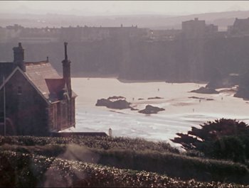 Movie still from “Magical Mystery Tour” (1967), directed by Ringo Starr – A view of a body of water with a house in the background; Extreme Wide shot, High angle