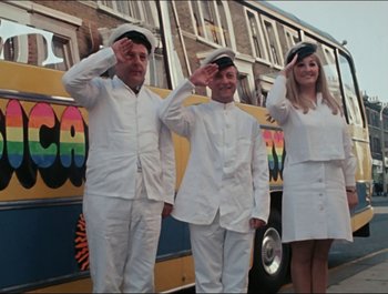 Movie still from “Magical Mystery Tour” (1967), directed by Ringo Starr – A group of men and women saluting while standing next to a bus; Wide shot, Low angle