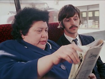 Movie still from “Magical Mystery Tour” (1967), directed by Ringo Starr – A man and a woman sitting next to each other on a bus; Close Up shot, Over the shoulder angle