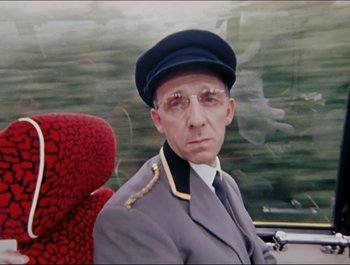 Movie still from “Magical Mystery Tour” (1967), directed by Ringo Starr – A man in a uniform sitting in a car; Close Up shot, Over the shoulder angle