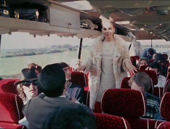 Movie still from “Magical Mystery Tour” (1967), directed by Ringo Starr – A group of people sitting on a red bus; Medium shot, Over the shoulder angle