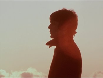Movie still from “Magical Mystery Tour” (1967), directed by Ringo Starr – A man standing in front of a sky with clouds in the background; Close Up shot, Low angle