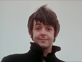 Movie still from “Magical Mystery Tour” (1967), directed by Ringo Starr – A man with a black jacket and a black shirt; Close Up shot, Low angle