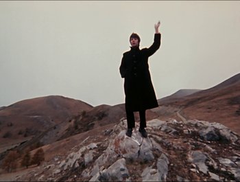 Movie still from “Magical Mystery Tour” (1967), directed by Ringo Starr – A man standing on top of a rock in the middle of a field; Wide shot, Low angle
