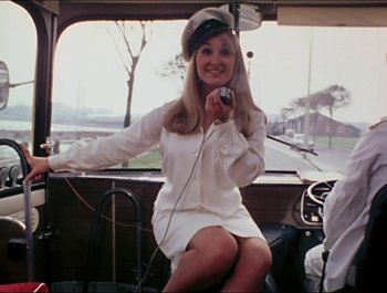 Movie still from “Magical Mystery Tour” (1967), directed by Ringo Starr – A woman sitting on the back of a car holding a camera; Medium shot, Low angle