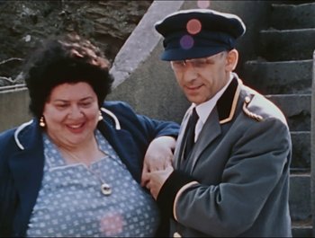 Movie still from “Magical Mystery Tour” (1967), directed by Ringo Starr – An older man and a younger woman posing for a picture; Medium shot, High angle