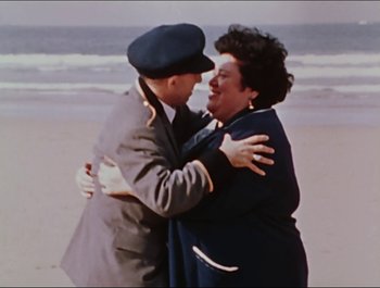 Movie still from “Magical Mystery Tour” (1967), directed by Ringo Starr – An older man and woman embracing on the beach; Medium shot, High angle