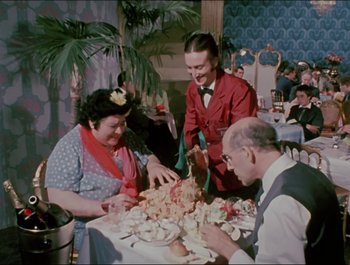Movie still from “Magical Mystery Tour” (1967), directed by Ringo Starr – A group of people sitting at a table with food on it; Medium shot, High angle