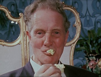 Movie still from “Magical Mystery Tour” (1967), directed by Ringo Starr – An older man is eating a piece of food; Close Up shot, Low angle