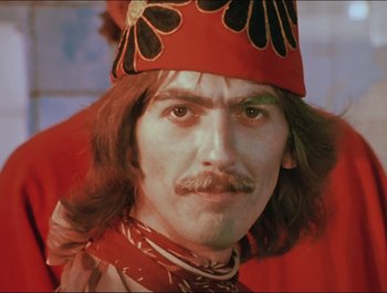 Movie still from “Magical Mystery Tour” (1967), directed by Ringo Starr – A person with long hair wearing a hat; Close Up shot, Low angle