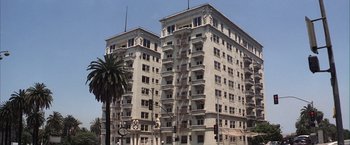 Movie still from “Magnolia” (1999), directed by Paul Thomas Anderson – A tall white building sitting next to a palm tree; Extreme Wide shot, Low angle