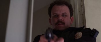 Movie still from “Magnolia” (1999), directed by Paul Thomas Anderson – A man holding a gun while wearing a black jacket; Close Up shot, Low angle