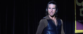 Movie still from “Magnolia” (1999), directed by Paul Thomas Anderson – A man with long black hair wearing a brown and black shirt; Close Up shot, Over the shoulder angle