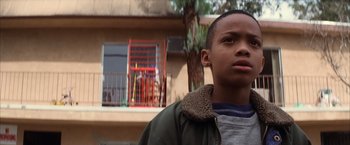 Movie still from “Magnolia” (1999), directed by Paul Thomas Anderson – A young boy standing in front of an apartment building; Close Up shot, Low angle