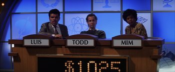 Movie still from “Magnolia” (1999), directed by Paul Thomas Anderson – Three men are sitting at a table in front of a $ 1 , 0 0 0 sign; Medium shot, Over the shoulder angle