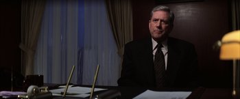Movie still from “Magnolia” (1999), directed by Paul Thomas Anderson – A man sitting at a table in front of papers; Close Up shot, Low angle