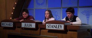 Movie still from “Magnolia” (1999), directed by Paul Thomas Anderson – A girl sitting in front of two other people at a table; Medium shot, High angle