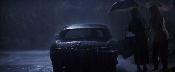 Movie still from “Magnolia” (1999), directed by Paul Thomas Anderson – A car is parked in the rain under an umbrella; Wide shot, Low angle