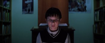 Movie still from “Magnolia” (1999), directed by Paul Thomas Anderson – A young boy in a dark room looking at the camera; Close Up shot, Low angle