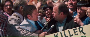 Movie still from “Magnum Force” (1973), directed by Ted Post – A group of people with microphones in front of a crowd; Medium shot, High angle