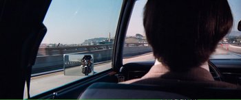 Movie still from “Magnum Force” (1973), directed by Ted Post – A person riding a motorcycle in a vehicle; Wide shot, Over the shoulder angle