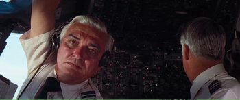 Movie still from “Magnum Force” (1973), directed by Ted Post – An older man is posing for a picture in front of an airplane cockpit; Close Up shot, Low angle