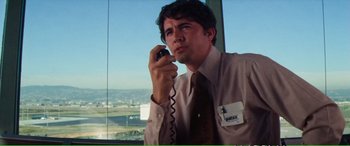 Movie still from “Magnum Force” (1973), directed by Ted Post – A man talking on a phone in front of an airport window; Medium shot, Low angle