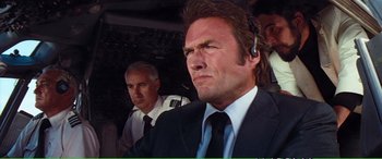 Movie still from “Magnum Force” (1973), directed by Ted Post – A man in a suit and tie with a headset on; Close Up shot, Low angle
