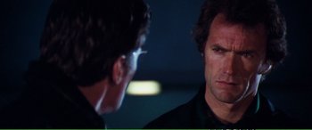 Movie still from “Magnum Force” (1973), directed by Ted Post – Two men talking to each other in front of a dark background; Close Up shot, Over the shoulder angle