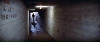 Movie still from “Magnum Force” (1973), directed by Ted Post – A person walking down a dark hallway in a building; Extreme Wide shot, High angle